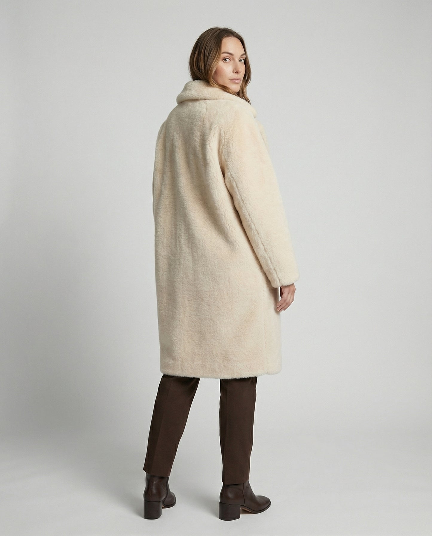 Woman wearing a cream-colored coat on a plain background