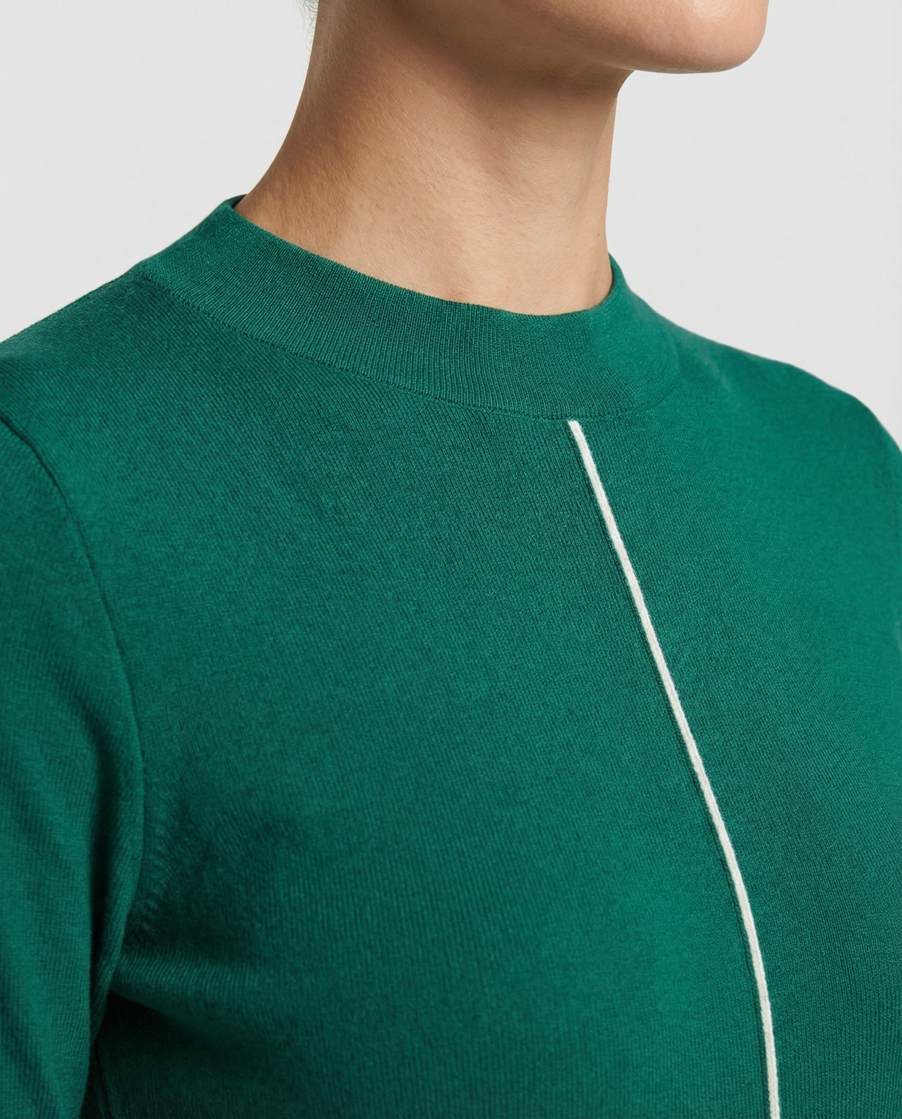 Green sweater with a white line detail on a neutral background