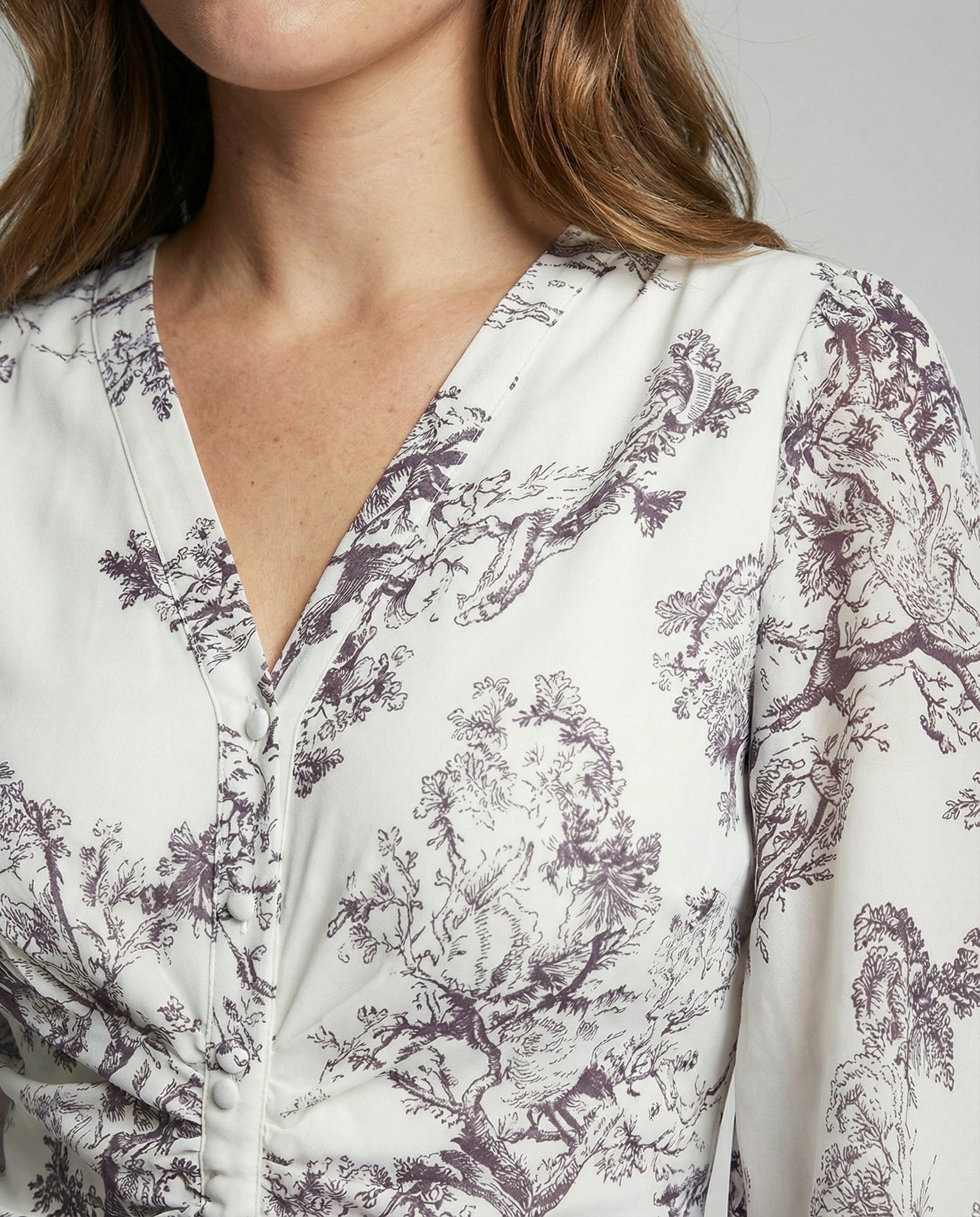 Close-up of a person wearing a white blouse with purple floral pattern