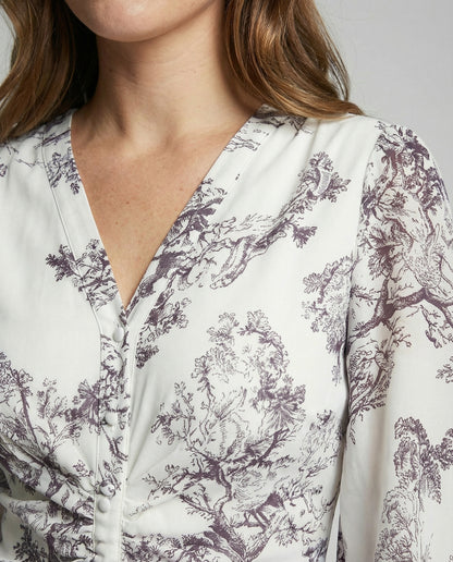 Close-up of a person wearing a white blouse with purple floral pattern