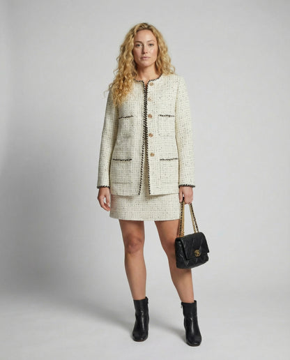 Woman wearing a tweed outfit with a handbag on a plain background