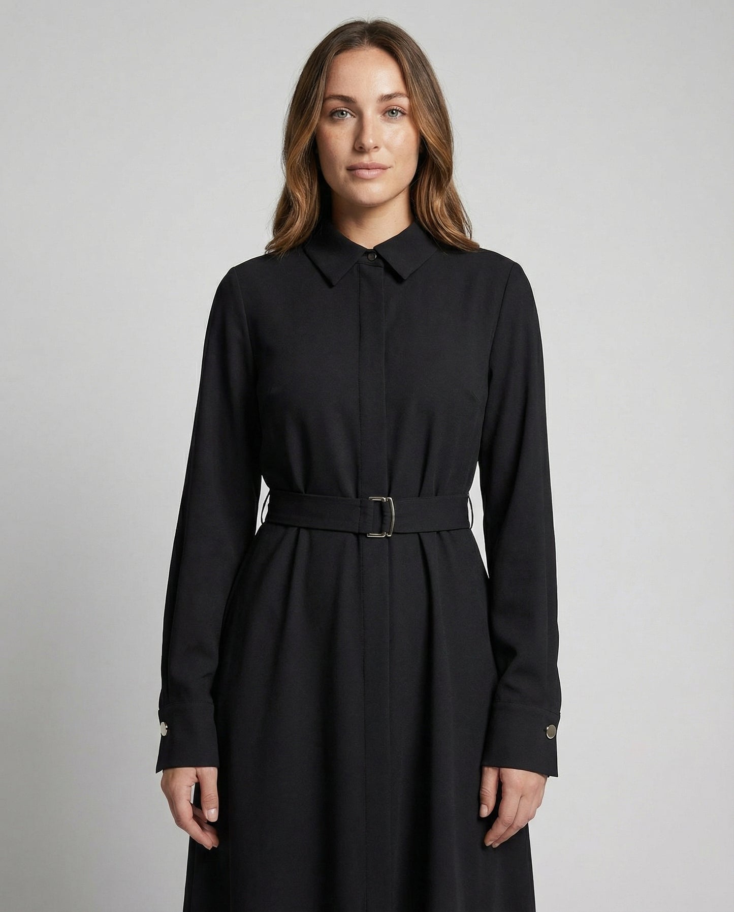 Woman wearing a black dress with a belt against a gray background