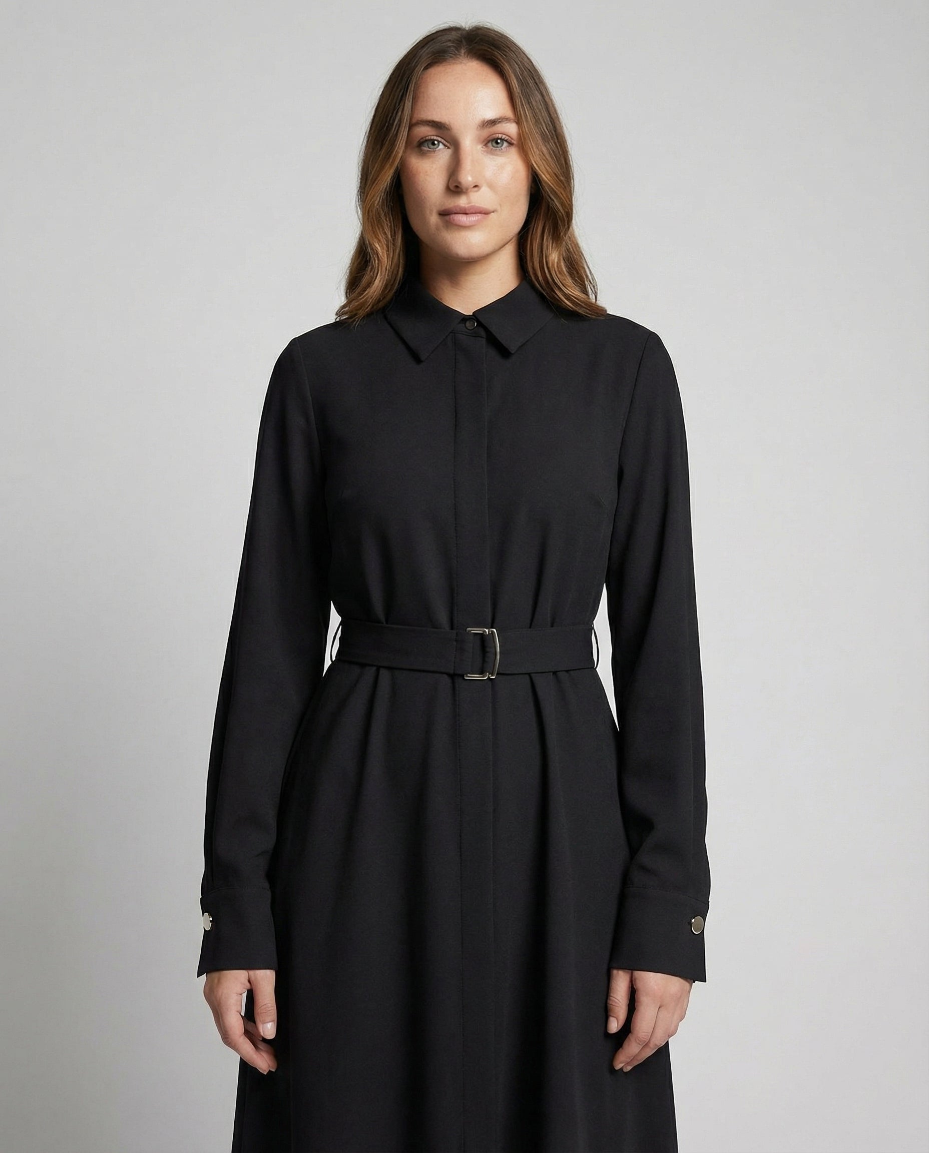 Woman wearing a black dress with a belt against a gray background