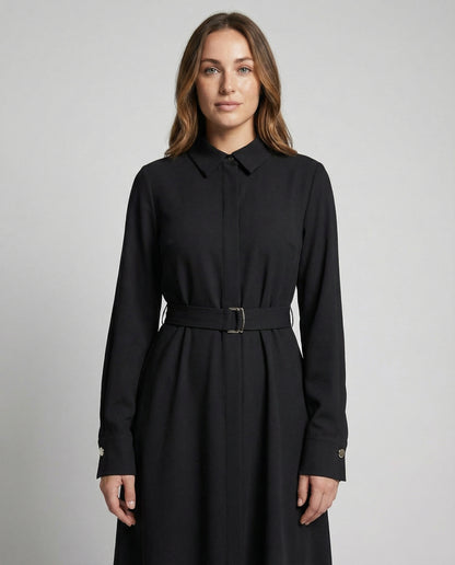 Woman wearing a black dress with a belt against a gray background