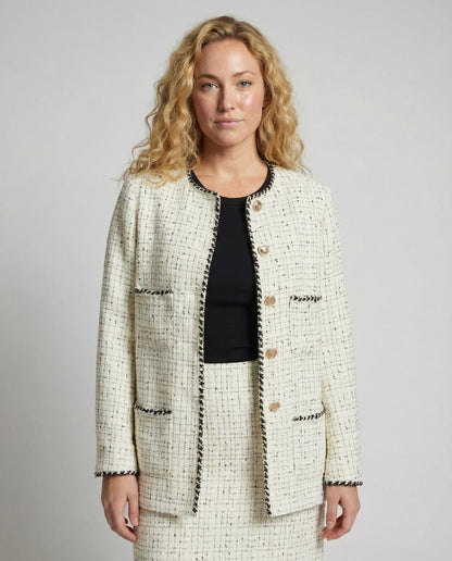 Woman wearing a tweed jacket and skirt set against a plain background