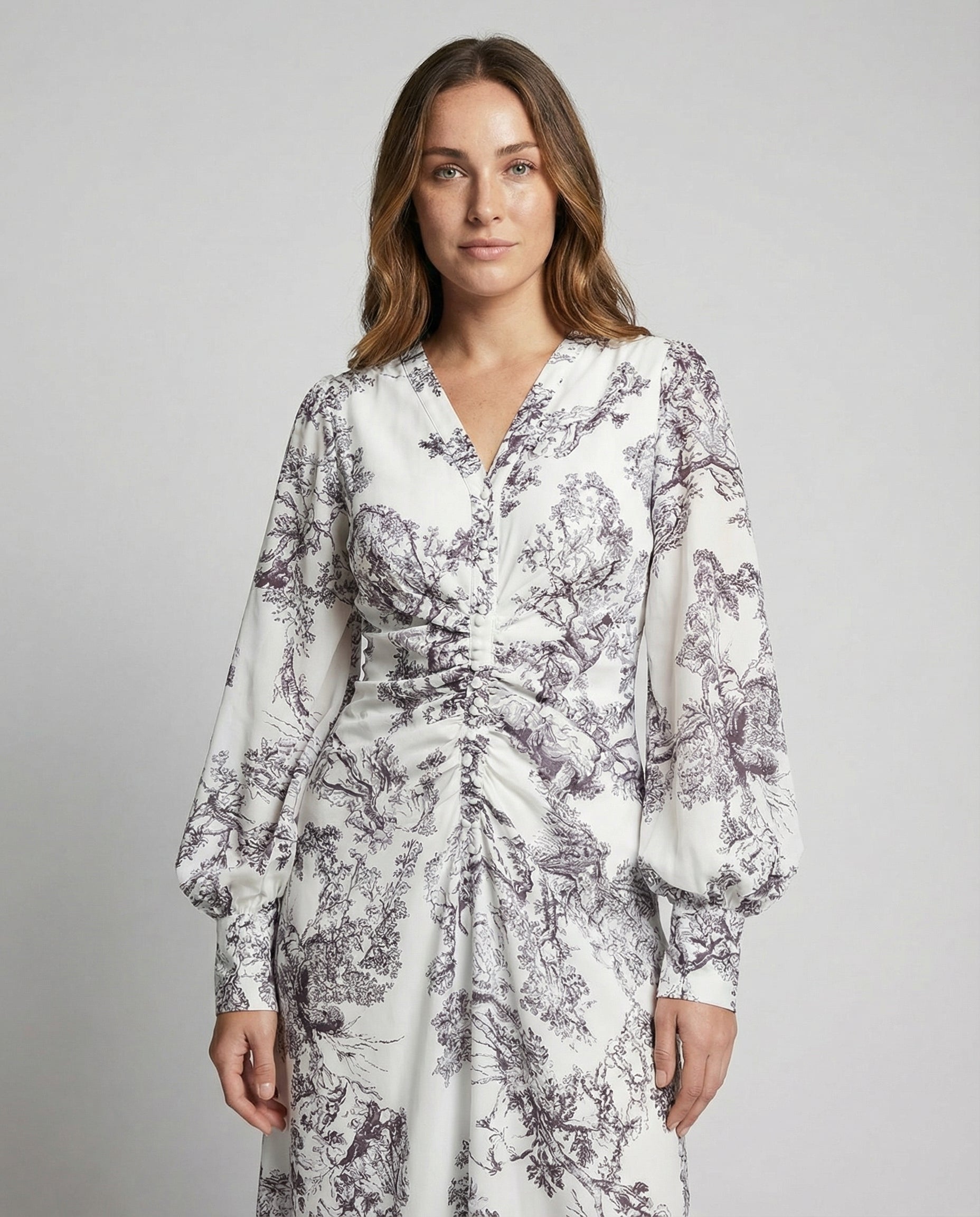 Woman wearing a white dress with black floral pattern on a gray background