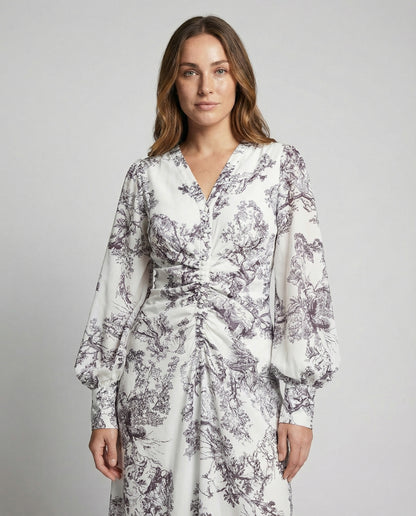 Woman wearing a white dress with black floral pattern on a gray background